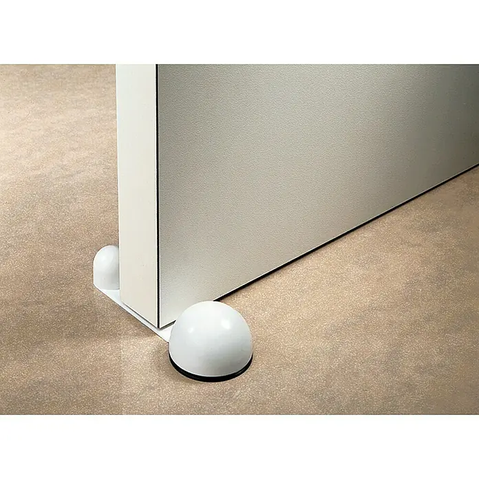 Inofix Tope de puerta retenedor 2035 - Plástico, Blanco, 4 ud. - Primer plano de un tope de puerta blanco en forma de cúpula fijado a la base de una puerta, evitando que se cierre de golpe. El diseño es funcional.