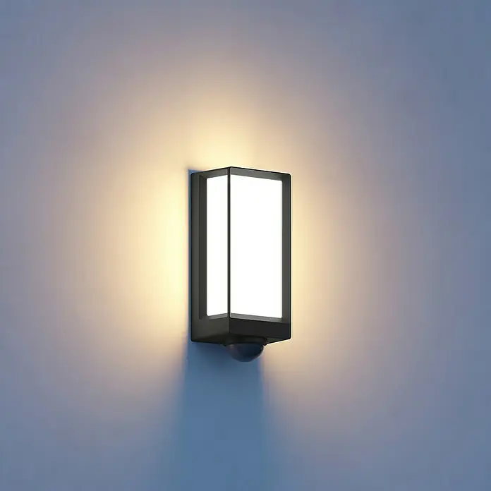 Steinel LED-Außenwandleuchte L 42 SC ANT - 12,6 W, 10,5 x 13,1 x 30,6 cm, Anthrazit, IP54 - Eine rechteckige Außenwandleuchte mit Bewegungssensor beleuchtet eine Wand. Das Licht ist warm und erhellt die Umgebung.