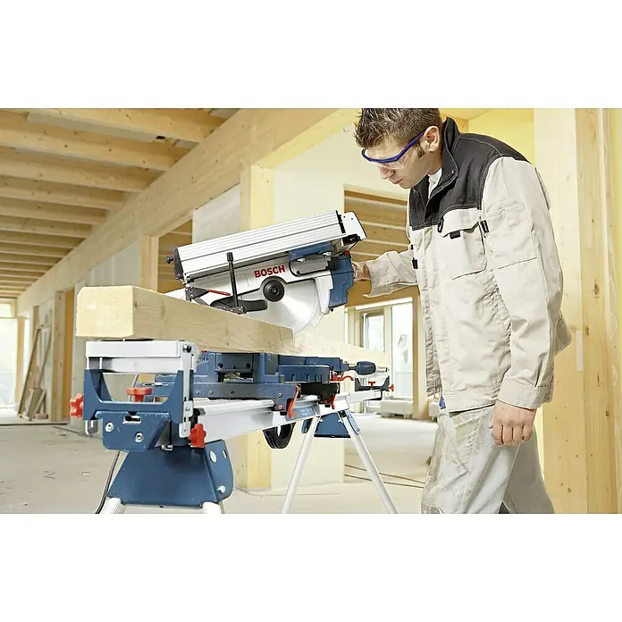 Bosch Professional Sägetisch GTA 2600 - Passend für: Stationärgeräte, Kappsägen, Paneelsägen, Belastbarkeit: 160 kg - Ein Handwerker benutzt eine Bosch Kapp- und Gehrungssäge mit einem Sägetisch zum Schneiden eines Holzstücks, um ein Bauprojekt durchzuführen.