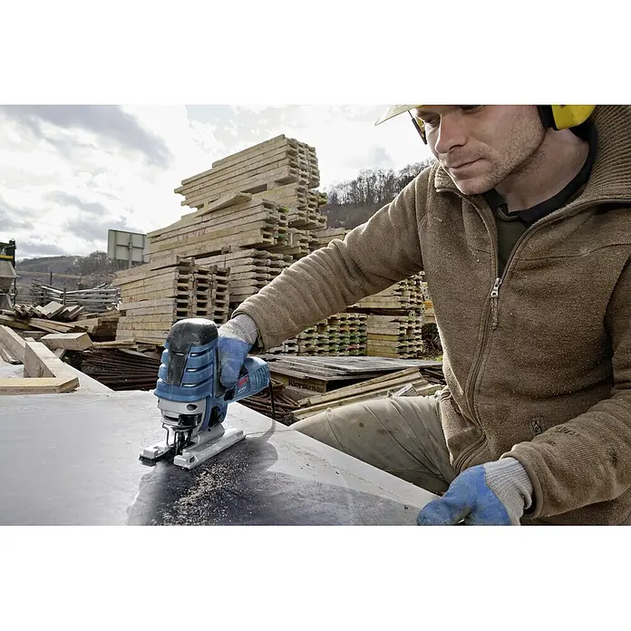 Bosch Professional Elektro-Pendelhubstichsäge GST 150 CE - 780 W, 500 /min - 3.100 /min, Anzahl Pendelhubstufen: 4 Stk. - Ein Mann benutzt eine blaue Bosch Stichsäge, um Metall zu schneiden. Er trägt dabei Handschuhe und Gehörschutz.