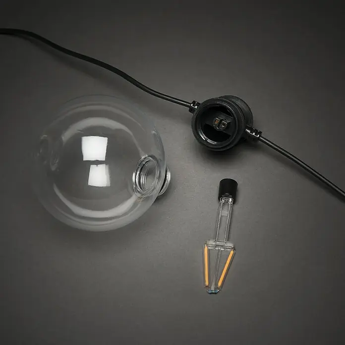 Konstsmide LED-Lichterkette - Außen, 4,5 cm, Bernstein, Rund, Solarbetrieben - Nahaufnahme einer zerlegten Edison-Glühbirne, die ihr transparentes Gehäuse und die Glühfäden zeigt.