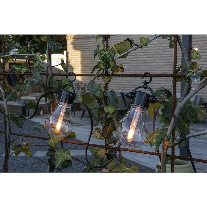 Konstsmide LED-Lichterkette - Außen, 4,5 cm, Bernstein, Oval, Solarbetrieben - Dekorative Glühbirnenkette, die an einem metallenen Rankgitter mit Efeu befestigt ist und warmes Licht verbreitet.