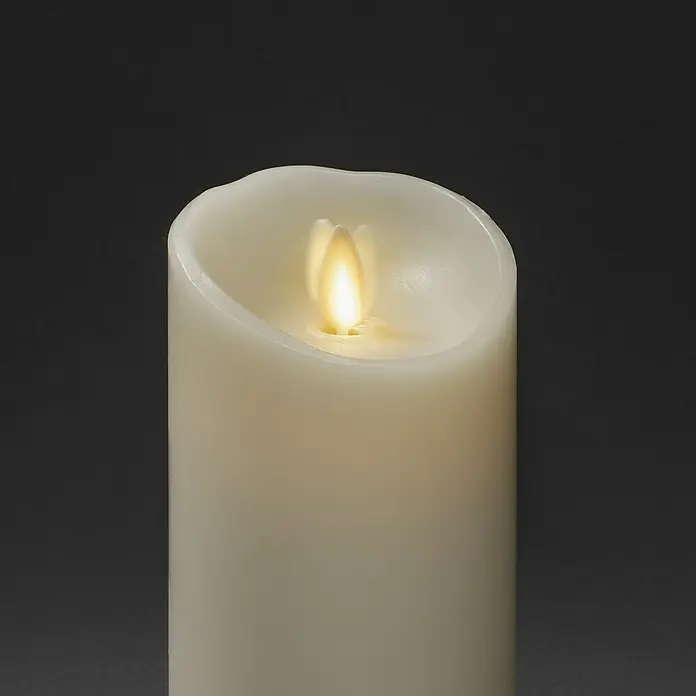 Konstsmide LED-Kerze - Beige, Wachs, 7,6 x 16,5 cm - Eine elfenbeinfarbene Stumpenkerze mit einer flackernden LED-Flamme vor einem neutralen, dunklen Hintergrund für eine gemütliche Atmosphäre.