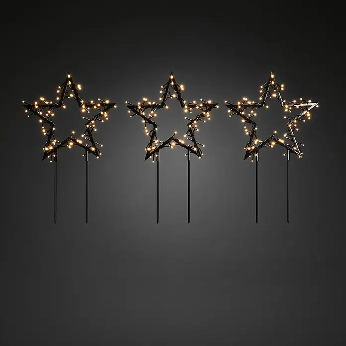 Konstsmide LED-Gartenstecker Stern 3er-SetSchwarz, Bernstein, Außen, 3 Stk. - Drei leuchtende Stern-Gartenstecker auf dunklem Hintergrund. Die Sterne sind mit warmweißen Lichtern geschmückt und bringen festliche Stimmung.
