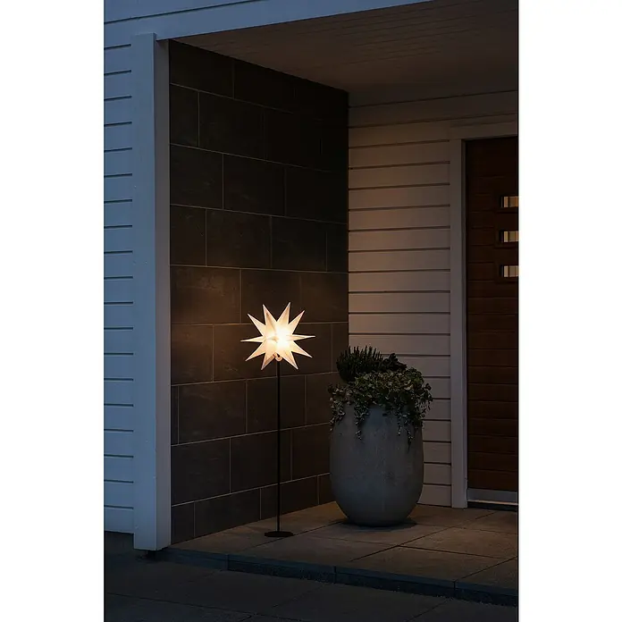 Konstsmide Standstern - Weiß, Warmweiß, LED, Netzbetrieben, 1 Stk. - Eine elegante Stern-Stehleuchte erhellt einen Eingangsbereich neben einem üppigen Pflanzgefäß.