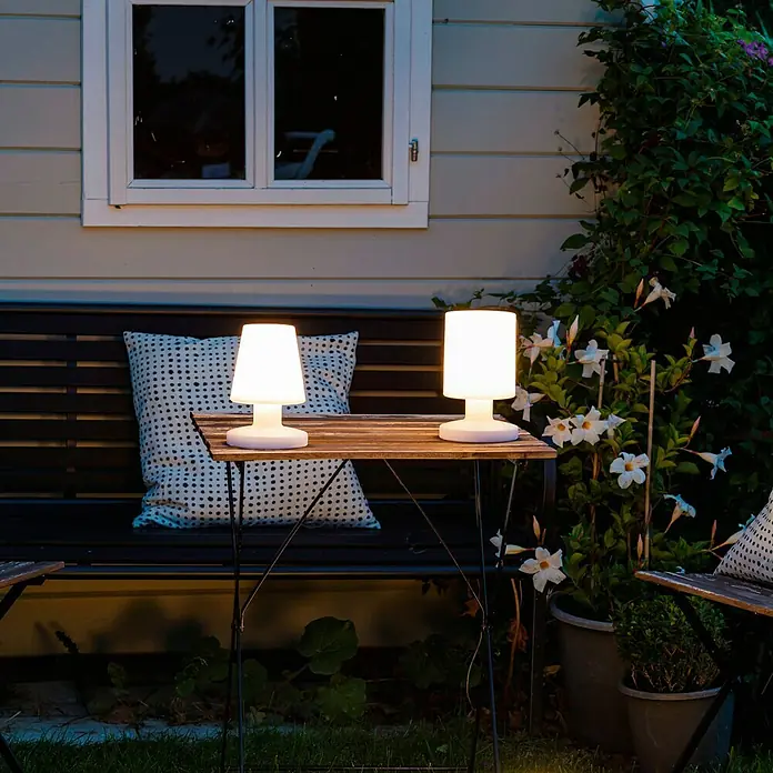 Reality Leuchten Akku-Tischleuchte Lora - 1,5 W, L x B x H: 13 x 13 x 20 cm, Weiß, Warmweiß - Zwei kabellose Tischleuchten auf einem Tisch im Freien, die eine gemütliche Atmosphäre schaffen.\n