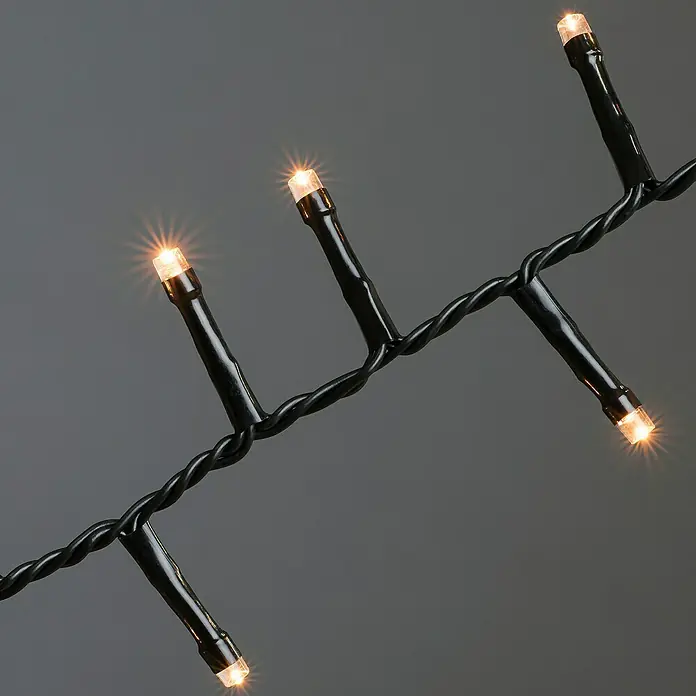 Konstsmide LED-Lichterkette - Innen, Lichtfarbe: Bernstein, Anzahl Leuchtmittel: 200 Stk., Netzbetrieben - Nahaufnahme von warmweiß leuchtenden LED-Lichterketten mit schwarzem Kabel, ideal für stimmungsvolle Dekorationen.