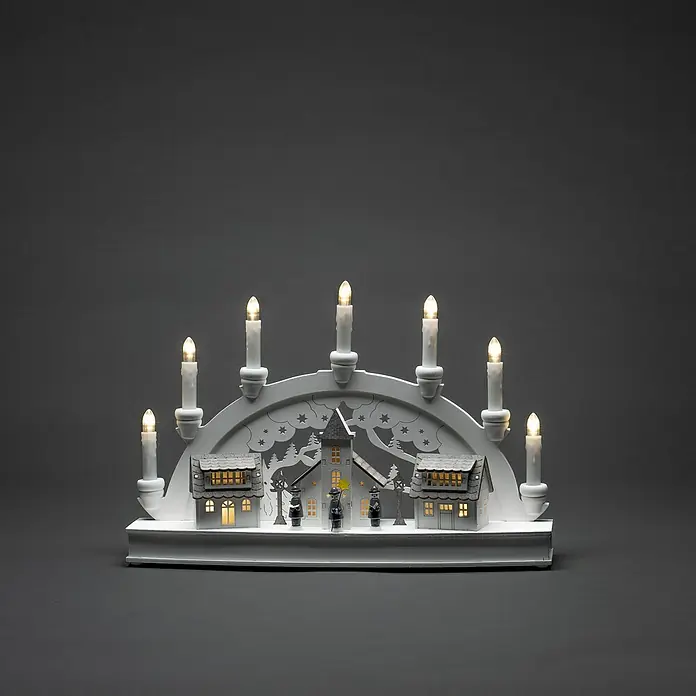 Konstsmide LED-Holzsilhouette Häuser - 10 x 43 x 28 cm, Weiß, Batteriebetrieben, Warmweiß - Ein dekorativer weißer Lichterbogen mit sieben Kerzen und einer winterlichen Häuserszene sorgt für festliche Stimmung.