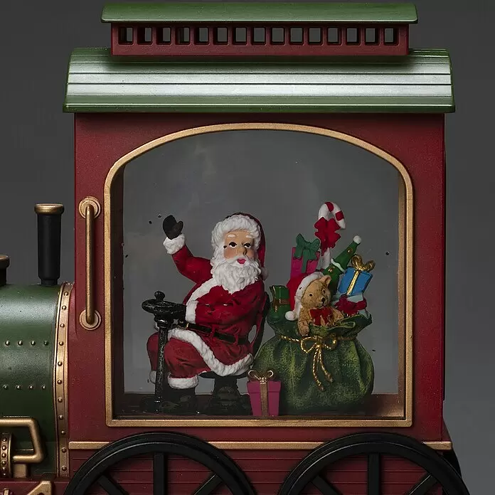Konstsmide LED-Schneelaterne Zug - Innen, Rot, Grün, 25 x 9 x 19,5 cm, Zug mit Weihnachtsmann, Batteriebetrieben - Rot-grüne Weihnachts-Eisenbahndekoration mit goldenen Akzenten. Im Inneren winkt der Weihnachtsmann neben einem Geschenkesack und einem Teddybär.
