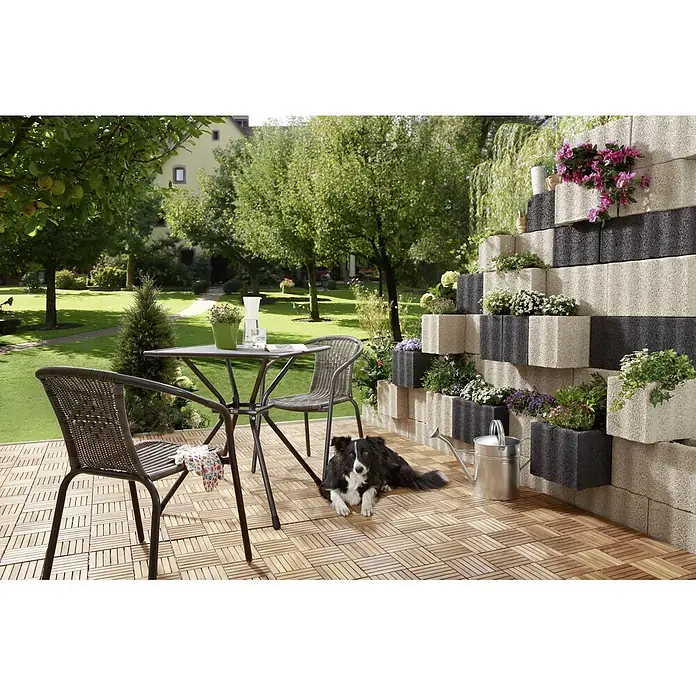 Christoph Pflanzstein Rasterstein - Anthrazit, 40 x 30 x 25 cm, Beton - Gartenszene mit Tisch, Stühlen, Dekoration und Hund. Das Arrangement betont die entspannte Atmosphäre im Freien.