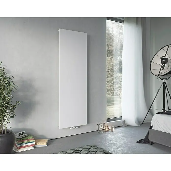 Ximax Raumheizkörper P1 Plan - B x H: 595 x 1.800 mm, Wärmeleistung bei Vorlauftemperatur von 75 °C (D: 50): 893 W, Weiß - Eine vertikale weiße Heizung an einer grauen Wand, ergänzt durch Bücher und Kerzen, verleiht dem Raum Wärme und Stil.