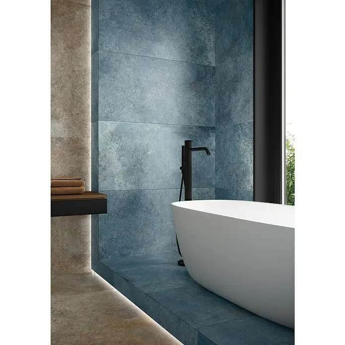 Feinsteinzeugfliese Blue Ocean - 59,7 x 119,7 cm, Blau, Matt - Elegantes Badezimmer mit freistehender Badewanne und blauen Fliesen, die ein modernes Ambiente schaffen.