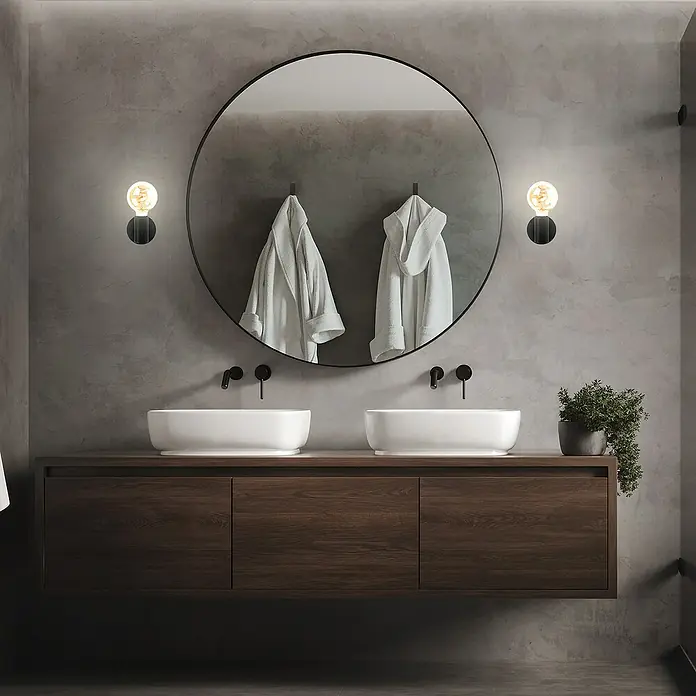 Briloner Wandleuchte KOSOL10 W, Schwarz, E27 - Ein modernes Badezimmer mit Doppelwaschtisch und rundem Spiegel, flankiert von zwei stilvollen Wandleuchten, die das elegante Design hervorheben.