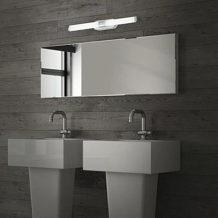 Briloner LED-Spiegelleuchte RUNT - 7 W, L x B x H: 40 x 4,5 x 6,5 cm, Chrom-matt, Neutralweiß - Moderne Badezimmer-Szene mit zwei Waschbecken, einem rechteckigen Spiegel und einer eleganten Lichtleiste vor dunkler Holzvertäfelung.