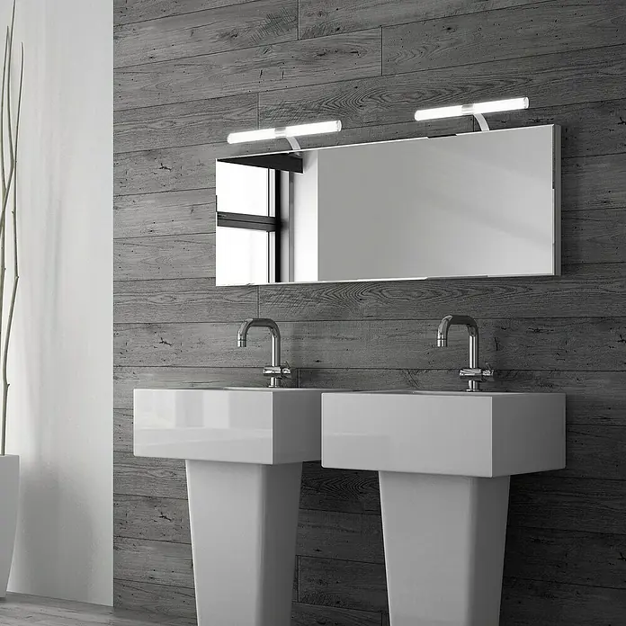 Briloner LED-Spiegelleuchte RUNT - 6 W, L x B x H: 40 x 10 x 16,5 cm, Chrom-matt, Neutralweiß - Modernes Badezimmerdesign mit Doppelwaschbecken und rechteckigem Spiegel mit Beleuchtung an einer grau holzvertäfelten Wand.
