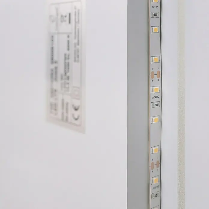 Camargue Lichtspiegel Juwa 1 - 60 x 80 cm - Nahaufnahme eines LED-Streifens mit der Aufschrift "DC 12V", der für Beleuchtungszwecke verwendet wird, und ein verschwommenes Schild auf der Wand.