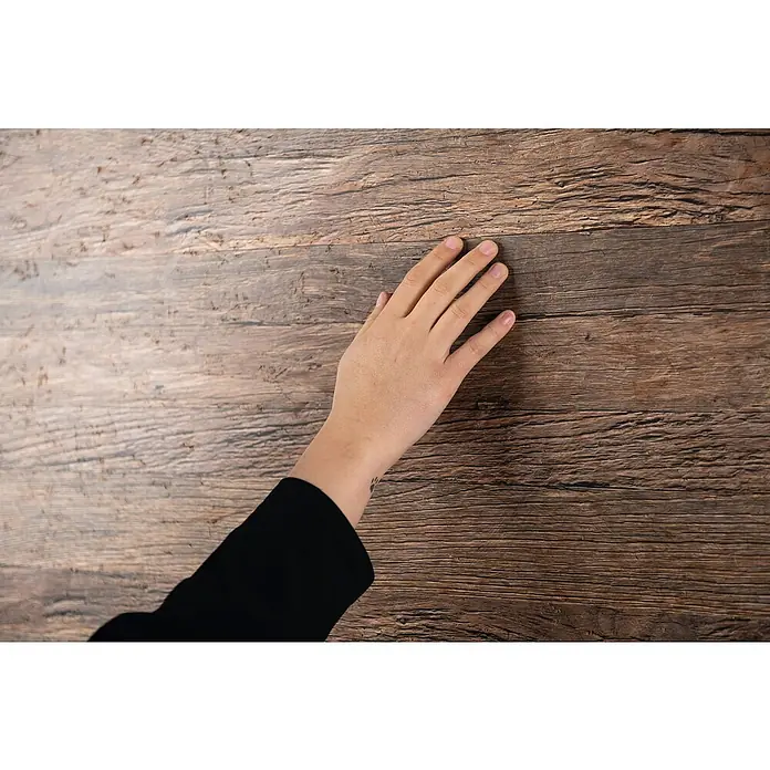 Egger Wandpaneel DecoWall - Annaba Eiche Natur, 125 cm x 66 cm x 12 mm - Eine Hand liegt auf einer polierten Holzoberfläche, die die natürliche Maserung und Wärme des Holzes hervorhebt.