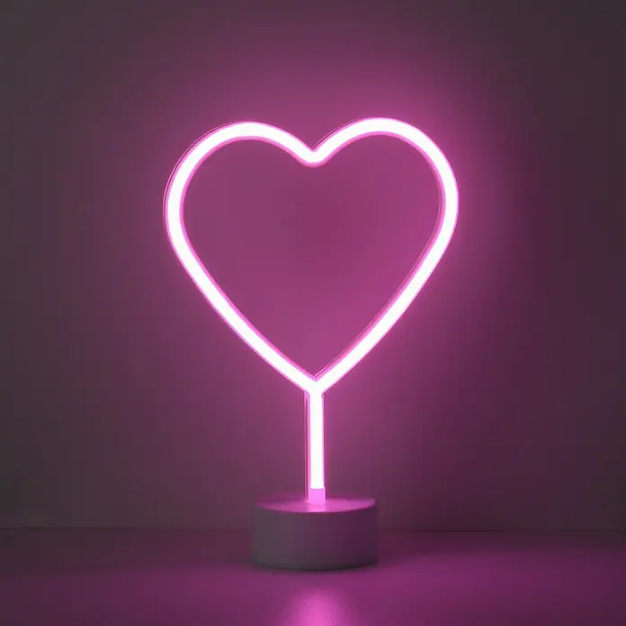 Just Light LED-Dekoleuchte Neon Herz - Neon Herz, L x B x H: 8,5 x 29,5 x 24 cm, Batteriebetrieben - Nahaufnahme einer leuchtenden, herzförmigen Neonlampe auf einem runden Sockel, die ein warmes, rosa Licht ausstrahlt.