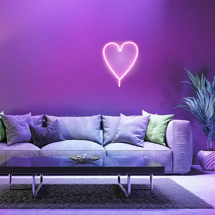 Just Light LED-Dekoleuchte Neon Herz - Neon Herz, L x B x H: 8,5 x 29,5 x 24 cm, Netzbetrieben - Elegantes Wohnzimmer mit stilvollem Sofa, Couchtisch und einer leuchtenden Herz-Neonlampe an der Wand. Pflanze im gemusterten Topf sorgt für Farbakzente.