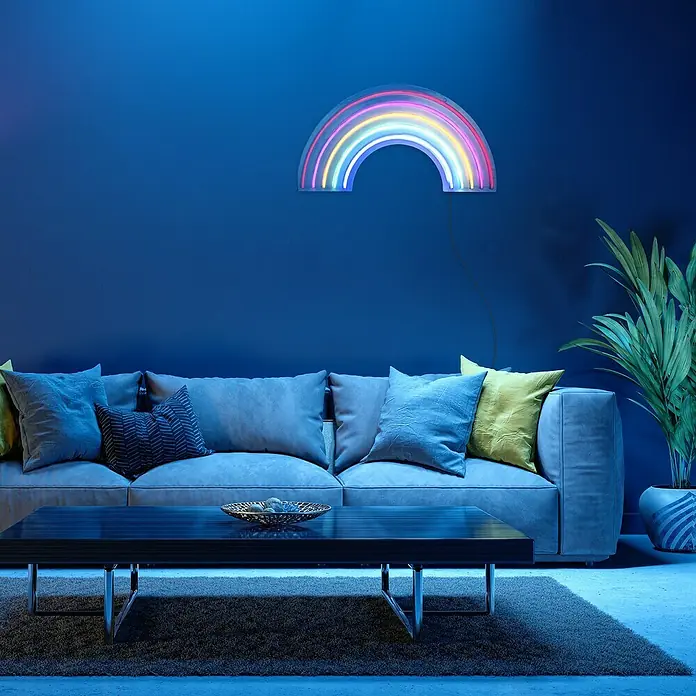Just Light LED-Dekoleuchte Neon Rainbow - Neon Rainbow, L x B x H: 8,5 x 29,5 x 24 cm, Netzbetrieben - Neon-Regenbogenleuchte über einem Sofa in einem blauen Wohnzimmer. Die Lampe ist ein farbenfroher Akzent und sorgt für eine gemütliche Atmosphäre.