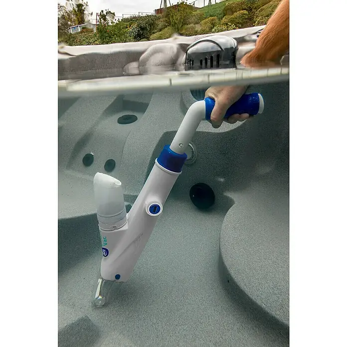Gre Poolsauger Spa Vac - Akkubetrieben - Eine Poolreinigungsbürste, die zum Reinigen eines Whirlpools verwendet wird, ist im Wasser zu sehen. Sie hat einen blauen Griff und einen transparenten Kopf.
