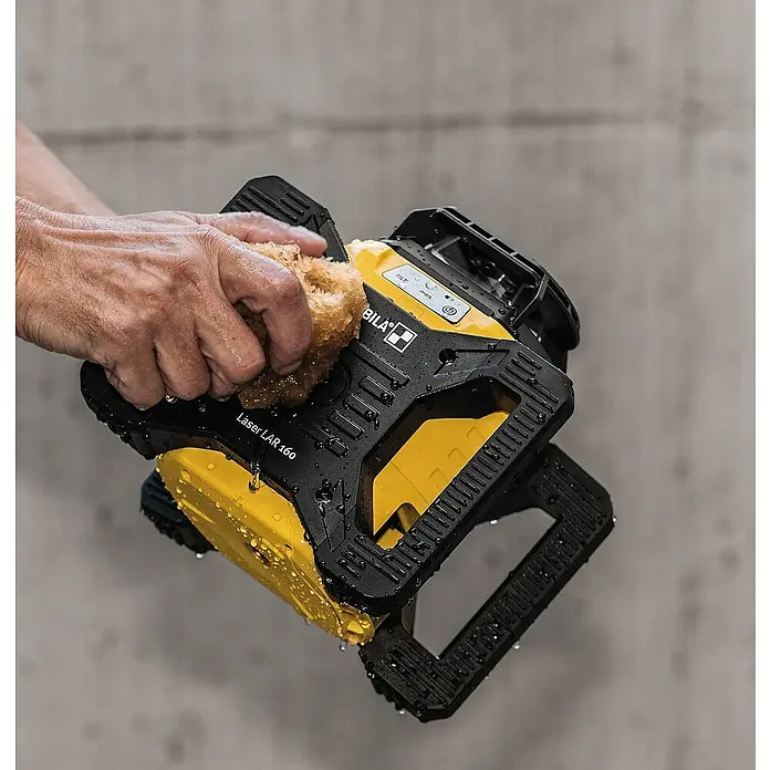 Stabila Rotationslaser LAR 160 - 9 -tlg. - Das Bild zeigt einen gelb-schwarzen BILA Laser LAR 160, der mit einem Schwamm gereinigt wird, um seine Robustheit und Widerstandsfähigkeit zu demonstrieren.
