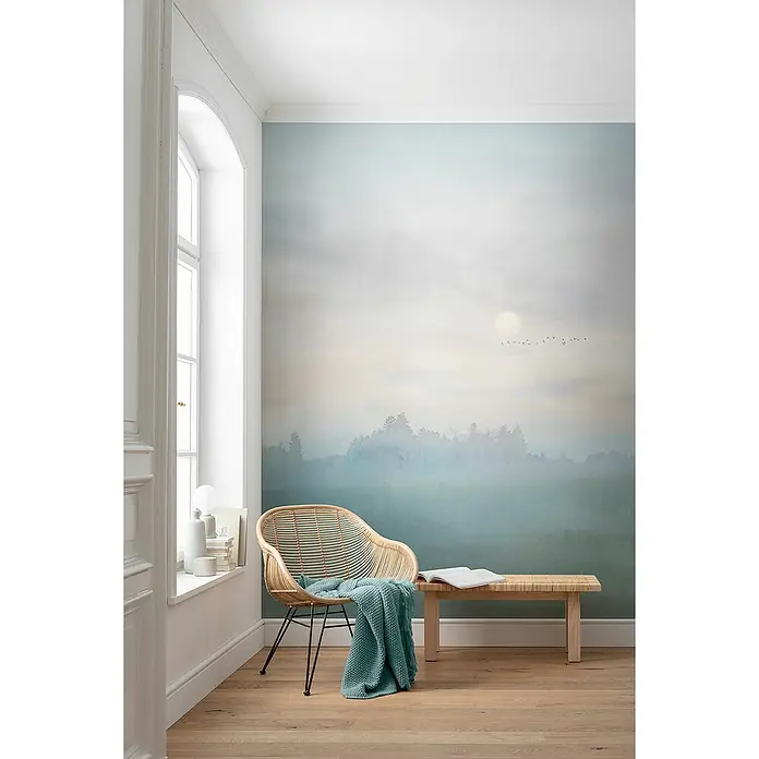 Komar Infinity 2 Fototapete Hazy Hush - B x H: 200 x 250 cm, Vlies - Einrichtungsidee mit einem Rattan-Stuhl, einer Holzbank und einer beruhigenden Wandtapete, die eine friedliche Atmosphäre schafft.