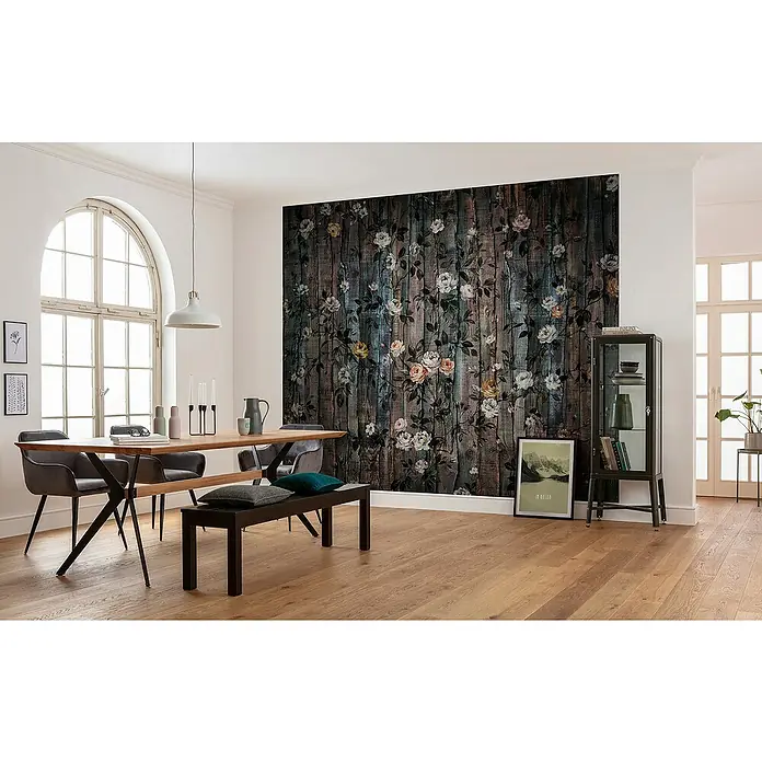 Komar Infinity 2 Fototapete Grande Giardino - B x H: 300 x 250 cm, Vlies - Ein stilvolles Esszimmer mit einem Holztisch, grauen Stühlen und einer Wand mit floralem Holzdesign. Die sanfte Beleuchtung schafft eine angenehme Atmosphäre.