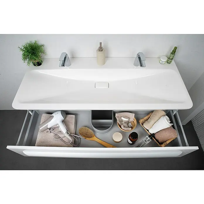 Lanzet M9 Einbauwaschbecken127,5 x 53,5 cm, Weiß, 2 Hahnlöcher - Ansicht von oben auf einen Waschtischunterschrank mit Auszug, gefüllt mit Badutensilien. Moderner Waschtisch mit viel Stauraum.