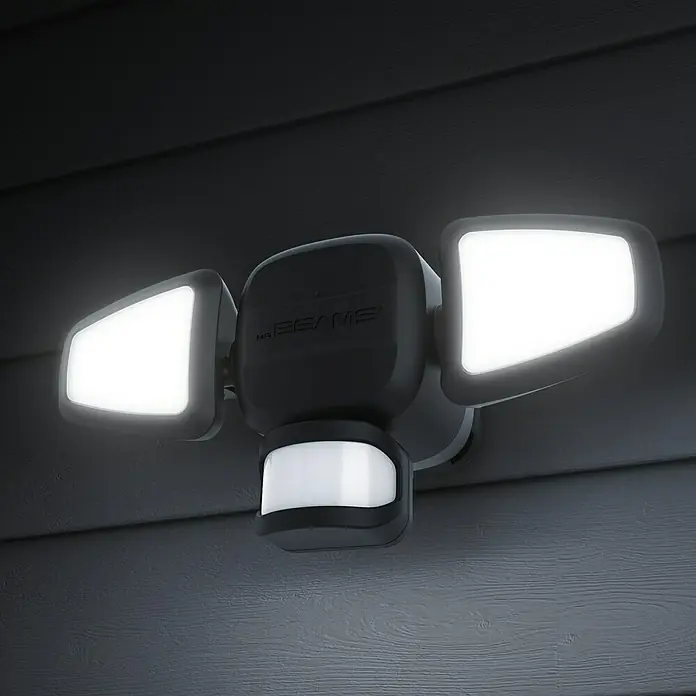 Mr. Beams LED-Strahler MB3200 - L x B x H: 27 x 9 x 10,5 cm, Neutralweiß, Schwarz - Nahaufnahme einer Mr. Beams Sicherheitsleuchte mit Bewegungsmelder, die an einer grauen Wand montiert ist und hell leuchtet.