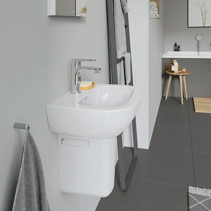 Duravit D-Code Waschbecken - 45 x 34 cm, Ohne Spezialglasur, Hahnloch: Mitte, Mit Überlauf, Weiß - Nahaufnahme eines modernen, weißen Duravit Waschbeckens mit Armatur, Seife und Handtuchhalter in einem stilvollen Badezimmer.