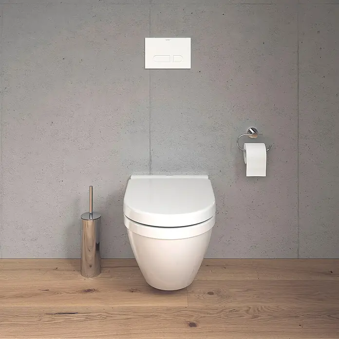 Duravit Starck 3 Wand-WC Typ 3 - Mit Spülrand, Ohne Spezialglasur, Spülform: Tief, WC Abgang: Waagerecht, Weiß - Nahaufnahme einer weißen Wandtoilette mit Spülkastenbetätigung und Toilettenpapierhalter vor einer grauen Betonwand.