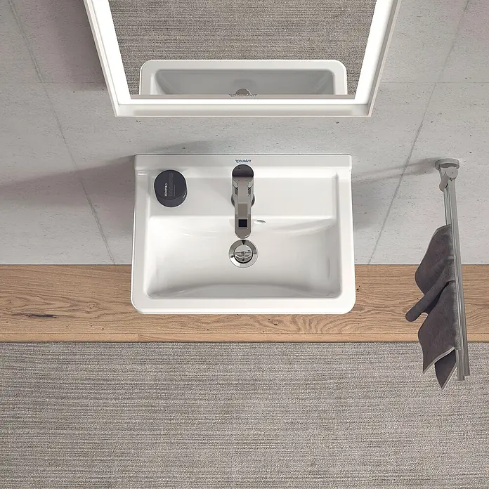 Duravit Starck 3 Waschbecken - 45 x 32 cm, Ohne Spezialglasur, Hahnloch: Mitte, Mit Überlauf, Weiß - Draufsicht auf ein weißes Duravit Waschbecken mit Armatur, Seife und Handtuch vor einem Spiegel. Elegantes Baddesign.