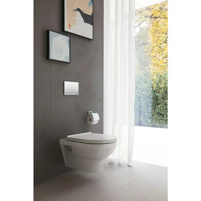 Duravit DuraStyle Wand-WC Basic - Spülrandlos, Ohne Spezialglasur, Spülform: Tief, WC Abgang: Waagerecht, Weiß - Moderne Badezimmergestaltung mit einer wandhängenden Toilette, Kunstwerken und einem Fenster mit Tageslicht für ein stilvolles Ambiente.