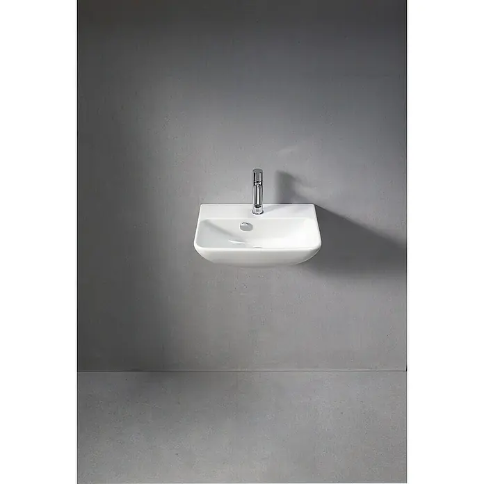 Duravit ME by Starck Waschbecken - 45 x 32 cm, Ohne Spezialglasur, Hahnloch: Mitte, Mit Überlauf, Weiß - Nahaufnahme eines modernen, wandmontierten Waschbeckens aus weißer Keramik mit einem eleganten Chromhahn vor einer grauen Wand.