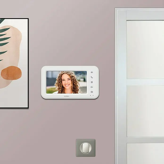 Avidsen Farb-Video-Türsprechanlage Elia - 2-Draht-Technik, Bildschirmgröße: 7″, 800 x 480 Pixel - Nahaufnahme eines Avidsen-Video-Türsprechanlagensystems mit einer Frau auf dem Bildschirm, das an einer Wand montiert ist.
