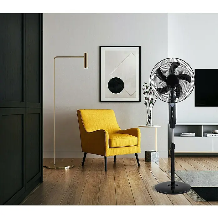 Ventilador de pie con batería y panel solar - 45 cm, 120 cm - Ventilador de pie en un salón moderno, proporcionando una brisa refrescante. Sillón amarillo, lámpara y obra de arte al fondo.