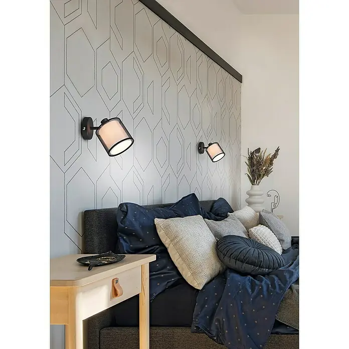 Trio Leuchten Burton Deckenstrahler - 28 W, L x B x H: 18,5 x 12,5 x 19,5 cm, Schwarz-matt, E14, 1 Stk. - Nahaufnahme von zwei stilvollen Wandleuchten neben einem Bett mit dekorativen Kissen und einem Nachttisch.
