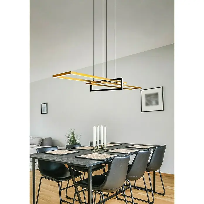 Trio Leuchten LED-Pendelleuchte Salinas - 34 W, L x B x H: 40 x 110 x 150 cm, Messing-matt, Warmweiß - Ein modernes Esszimmer mit einem schwarzen Tisch und Stühlen unter einer rechteckigen Gold- und Schwarzleuchte.