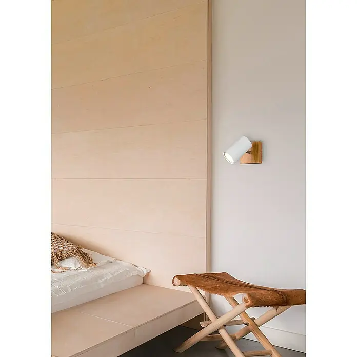 Trio Leuchten Marley Deckenstrahler - 15 W, L x B x H: 12 x 9 x 16 cm, Weiß/Holz, GU10, 1 Stk. - Eine moderne Wandleuchte in Weiß und Holz, die ein warmes Licht ausstrahlt, hängt neben einem stilvollen Bett und einem Hocker.