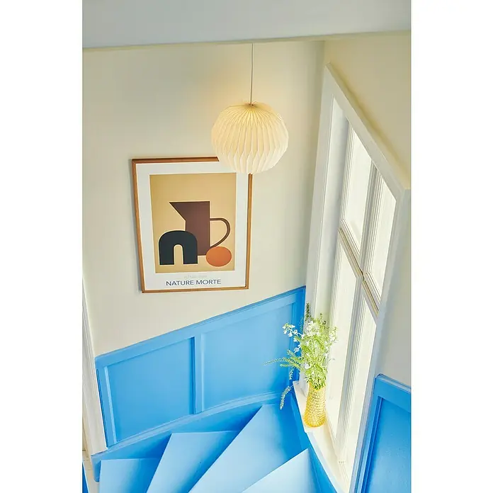 Nordlux Lampenschirm BELLOY - L x B x H: 30 x 30 x 26 cm, Weiß, 30 cm - Eine einzigartige Ansicht eines Treppenhauses mit blauen Stufen, einem Kunstwerk und einer Hängelampe, die dem Raum einen stilvollen Touch verleiht.