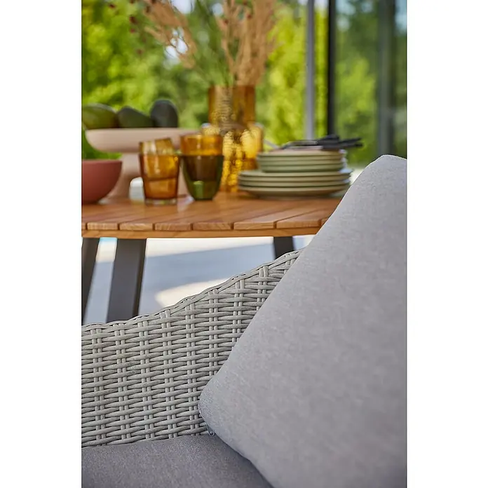 Sunfun Paula Gartensessel XLB x T x H: 70 x 75 x 82 cm, Hellgrau, Akazie - Nahaufnahme eines eleganten Gartentisches mit Geschirr und Dekoration, ergänzt durch einen stilvollen Rattansessel mit Polster.