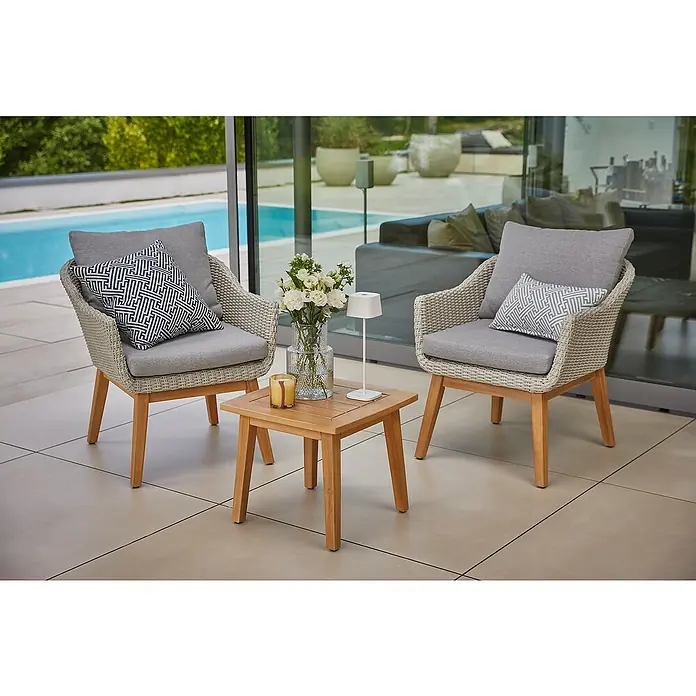 Sunfun Paula Gartensessel XL - Akazie, Hellgrau, B x T x H: 70 x 75 x 82 cm - Zwei stilvolle Rattansessel mit grauen Kissen und einem kleinen Holztisch mit Blumen und Lampe für den Außenbereich.