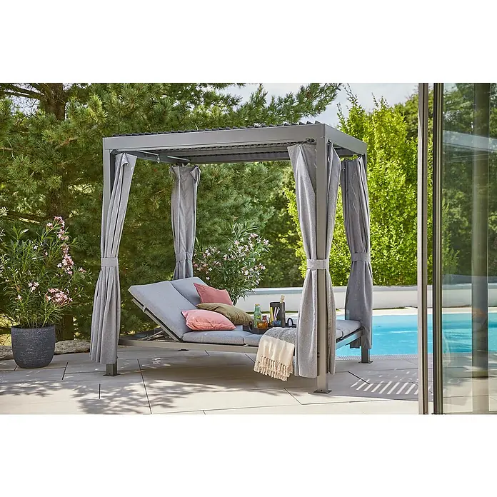 Sunfun Maja Loungeliege - L x B x H: 222 x 159 x 230 cm, Metall, Grau - Eine elegante graue Outdoor-Lounge mit Vorhängen und Kissen neben einem Pool, umgeben von grüner Vegetation. Perfekt zum Entspannen im Freien.