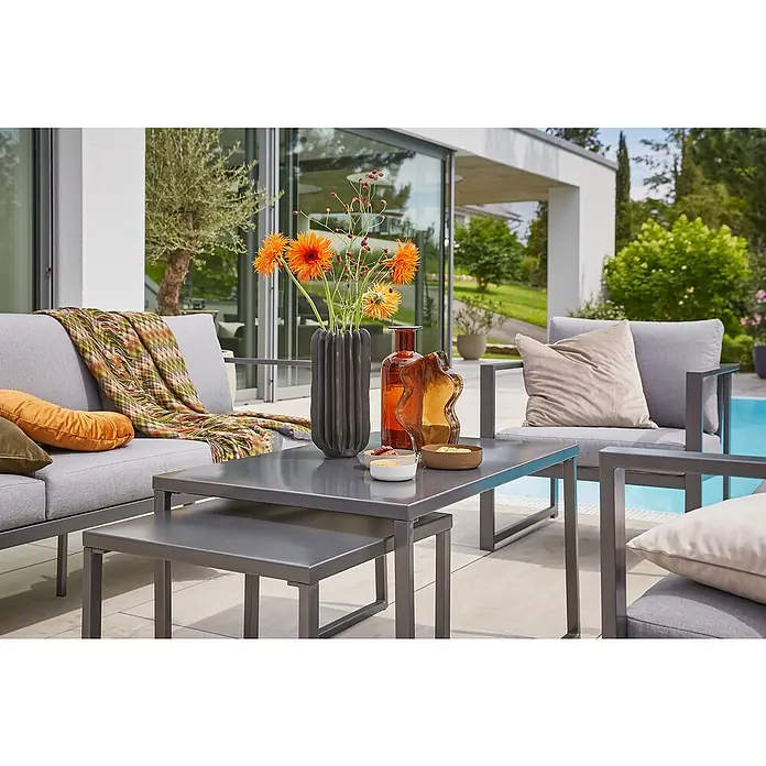 Sunfun Maja Slim Garten-Couchtisch - L x B x H: 50 x 50 x 43 cm, Anthrazit - Moderne Gartengarnitur mit grauem Sofa, Sesseln und Couchtischen. Dekorative Vasen und Kissen verleihen dem Arrangement eine einladende Atmosphäre.