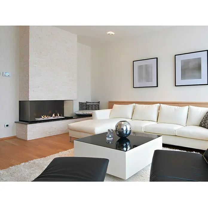 Purline Bloque de combustión F96120 - 120 x 20 x 9 cm, Acero inoxidable - Una sala de estar elegante con una chimenea moderna, un sofá blanco y una mesa de centro elegante que crean un ambiente acogedor.