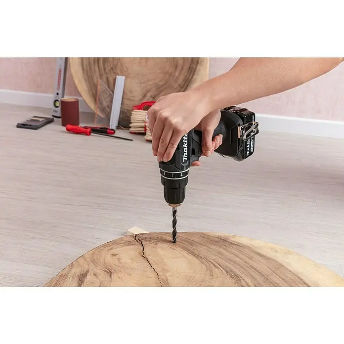 Craftomat Broca para madera - 8 pzs., Diámetro de la broca: 10 mm - Taladro inalámbrico Makita perforando un trozo de madera. La herramienta es negra y se adapta cómodamente a la mano.