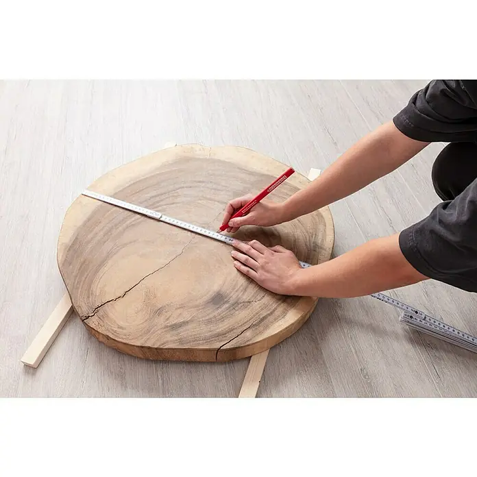 BAUHAUS Zimmermannsbleistift - Lindenholz, Länge: 240 mm - Eine Person misst eine Baumscheibe mit einem roten Stift und einem Zollstock, um die Maße für ein DIY-Projekt festzulegen.