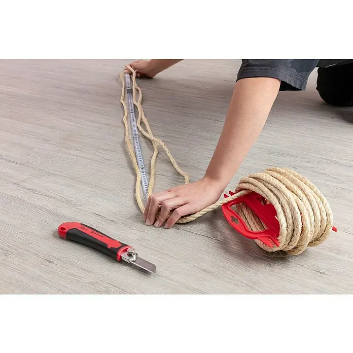 Stabilit Sisalseil - 8 mm x 10 m, 3-schäftig gedreht - Person misst Seil mit Maßband, Cutter liegt bereit, Seil auf roter Spule. Handwerkliches Projekt im Gange.