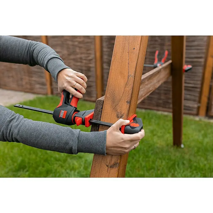 Bessey Einhandzwinge EZ 360-60Spannweite: 600 mm, Ausladung: 80 mm - Eine Person verwendet eine BESSEY Einhandzwinge, um Holzstücke zu befestigen, ideal für schnelle und sichere Fixierungen bei Bauprojekten.